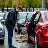 Стоянка с автомобилями - покупатель осматривает автомобиль с повреждениями кузова