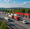 По шоссе мимо заправочной станции едут несколько грузовых машин