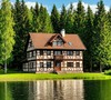 Большой фахверковый дом на берегу озера на фоне леса летом
