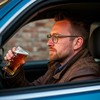 Водитель за рулем автомобиля пьет пиво