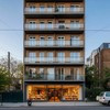 Фасад жилой многоэтажки, внизу на первом этаже вход в маленький магазин, где раньше были квартиры