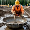 Строитель перемешивает бетон в металлическом корыте