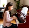 Девушка играет на фортепиано в комнате квартиры
