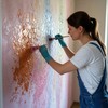 Маляр красит стену декоративными красками для создания уникального интерьера помещения