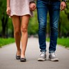 Девушка в туфлях без каблука и парень в кроссовках гуляют по парку