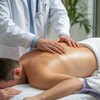 Врач делает лечебный массаж спины пациента, который лежит на животе