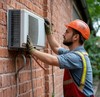 Сотрудник ремонтной компании снимает сплит-систему со стены